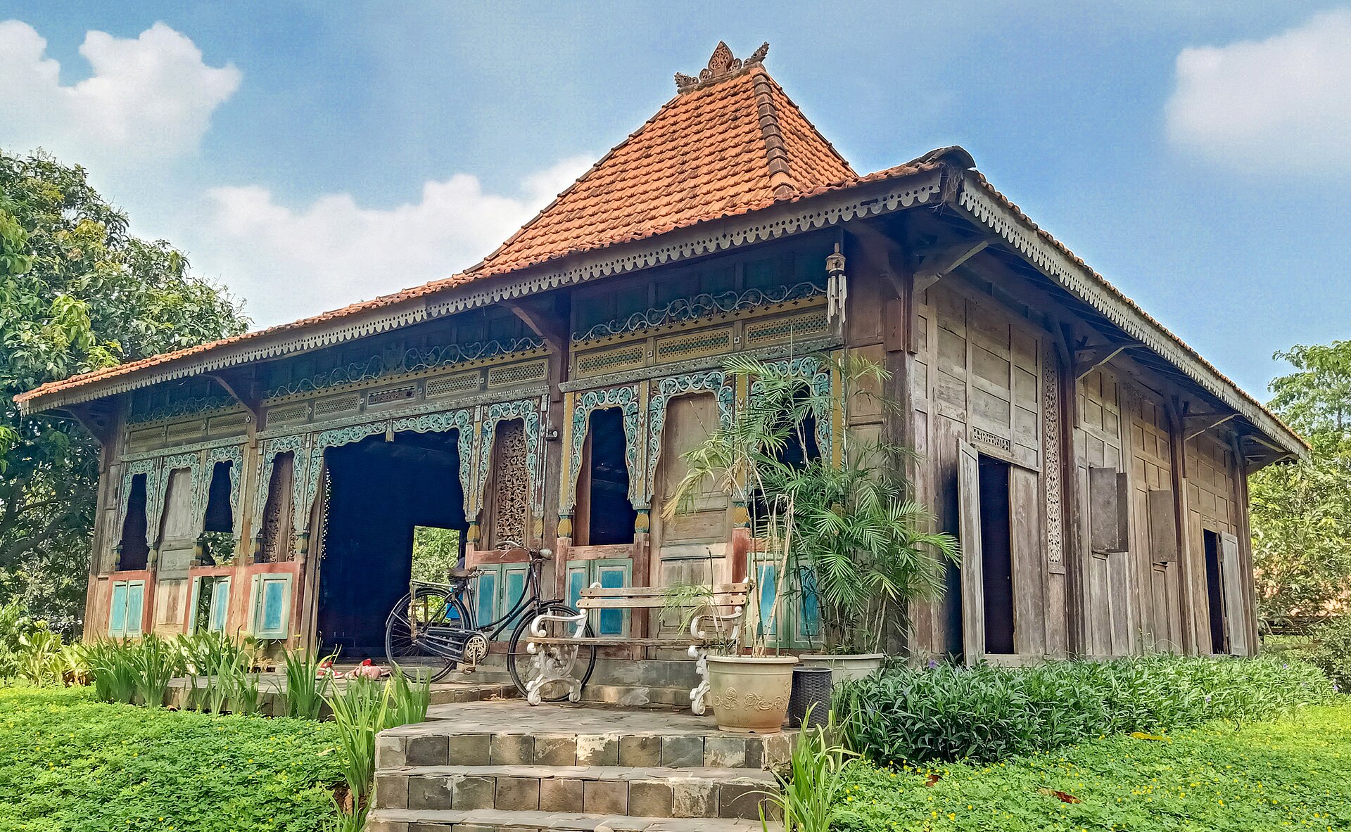 Rumah joglo kayu dengan taman rumput terawat